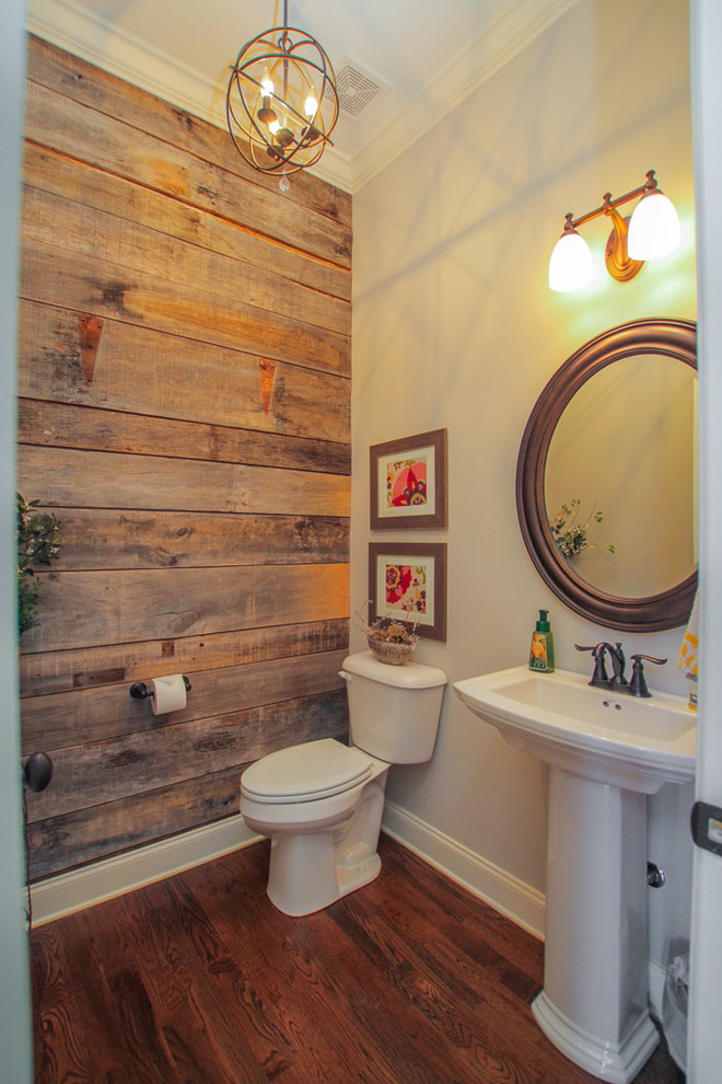 Foto på ett mellanstort rustikt toalett, med en toalettstol med hel cisternkåpa, brun kakel, grå väggar, mörkt trägolv, ett piedestal handfat, bänkskiva i akrylsten och brunt golv