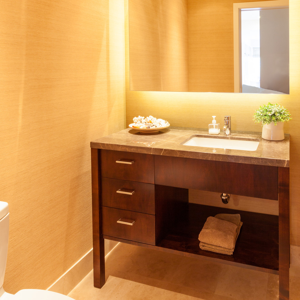 Réalisation d'un petit WC et toilettes minimaliste en bois foncé avec un placard en trompe-l'oeil, un plan de toilette en granite, un mur jaune, un sol en travertin, un lavabo encastré et un sol beige.
