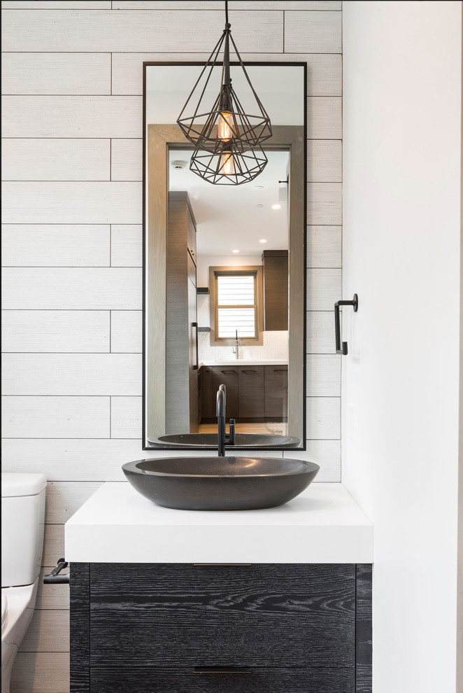 Example of a small trendy white tile and porcelain tile powder room design in Salt Lake City with flat-panel cabinets, black cabinets, white walls, a vessel sink, solid surface countertops and white countertops