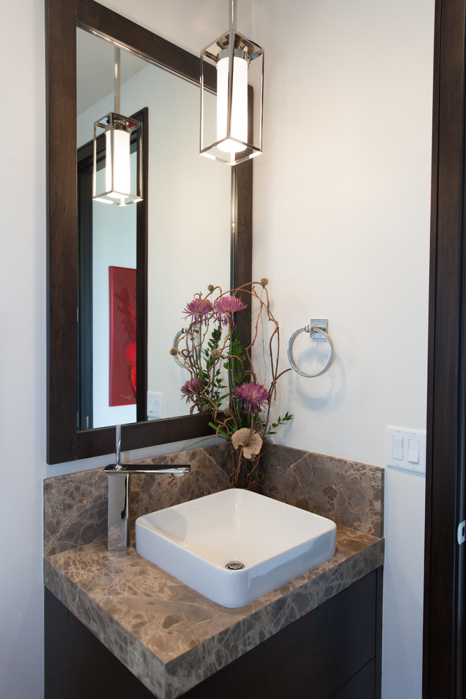 Cette image montre un petit WC et toilettes traditionnel en bois foncé avec une vasque, un placard à porte plane, un plan de toilette en granite, un mur blanc et un plan de toilette marron.