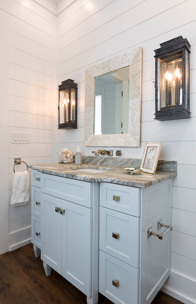 Esempio di un bagno di servizio stile marinaro di medie dimensioni con ante in stile shaker, ante blu, pareti bianche, pavimento in legno massello medio, lavabo sottopiano, top in marmo, pavimento marrone e top grigio