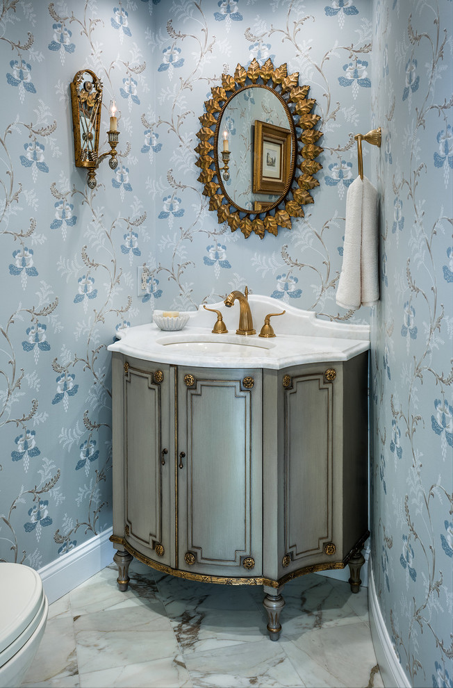 Idées déco pour un petit WC et toilettes classique avec des portes de placard bleues, du carrelage en marbre, un mur bleu, un sol en marbre et un plan de toilette blanc.