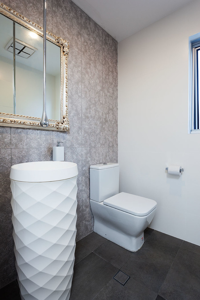 Стильный дизайн: туалет в современном стиле с раковиной с пьедесталом, серой плиткой, бежевыми стенами и полом из керамической плитки - последний тренд