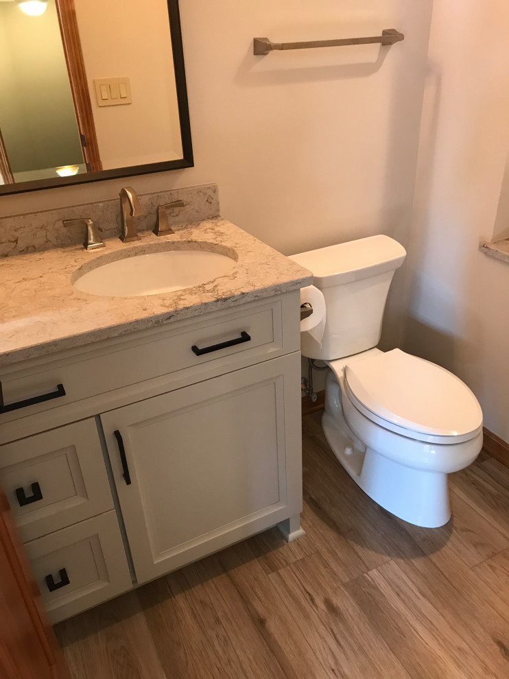Bild på ett mellanstort vintage grå grått toalett, med släta luckor, grå skåp, en toalettstol med separat cisternkåpa, beige kakel, kakelplattor, beige väggar, vinylgolv, ett undermonterad handfat, bänkskiva i kvarts och beiget golv