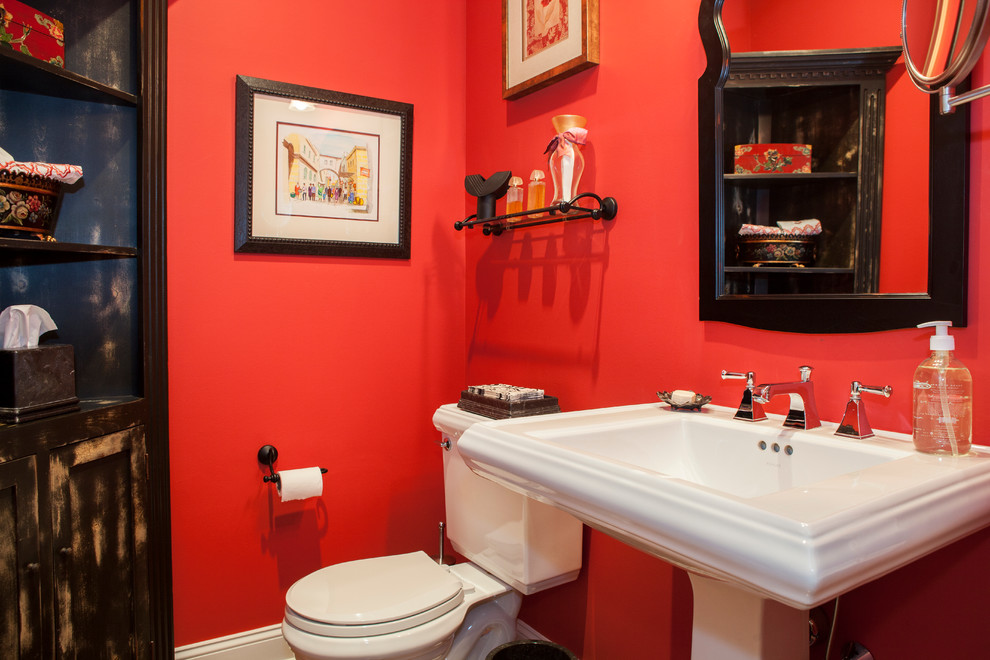 Bild på ett litet funkis toalett, med ett piedestal handfat, skåp i slitet trä, en toalettstol med separat cisternkåpa, röda väggar och klinkergolv i keramik