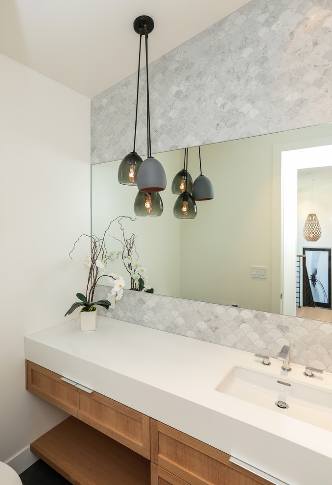 Immagine di un bagno di servizio design con ante in stile shaker, ante in legno chiaro, piastrelle grigie, pareti bianche e lavabo sottopiano