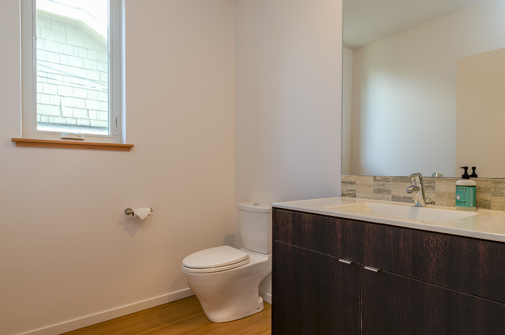 Medium sized modern cloakroom in Seattle with an integrated sink, flat-panel cabinets, dark wood cabinets, solid surface worktops, a one-piece toilet, beige tiles, porcelain tiles and white walls.