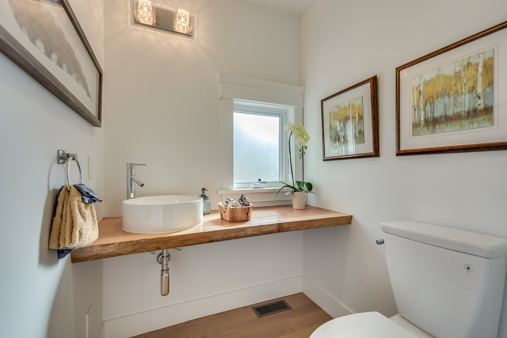 Réalisation d'un petit WC et toilettes design avec WC séparés, un mur blanc, parquet clair, une vasque, un plan de toilette en bois et un plan de toilette marron.