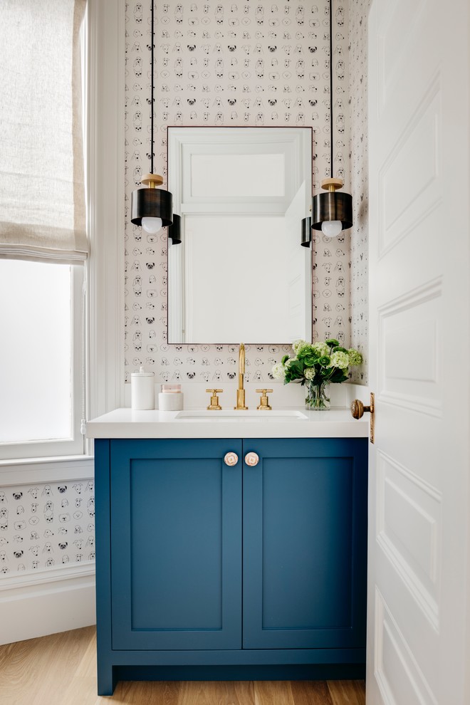 Klassische Gästetoilette mit Schrankfronten im Shaker-Stil, blauen Schränken, weißer Wandfarbe, braunem Holzboden, Unterbauwaschbecken, braunem Boden und weißer Waschtischplatte in San Francisco