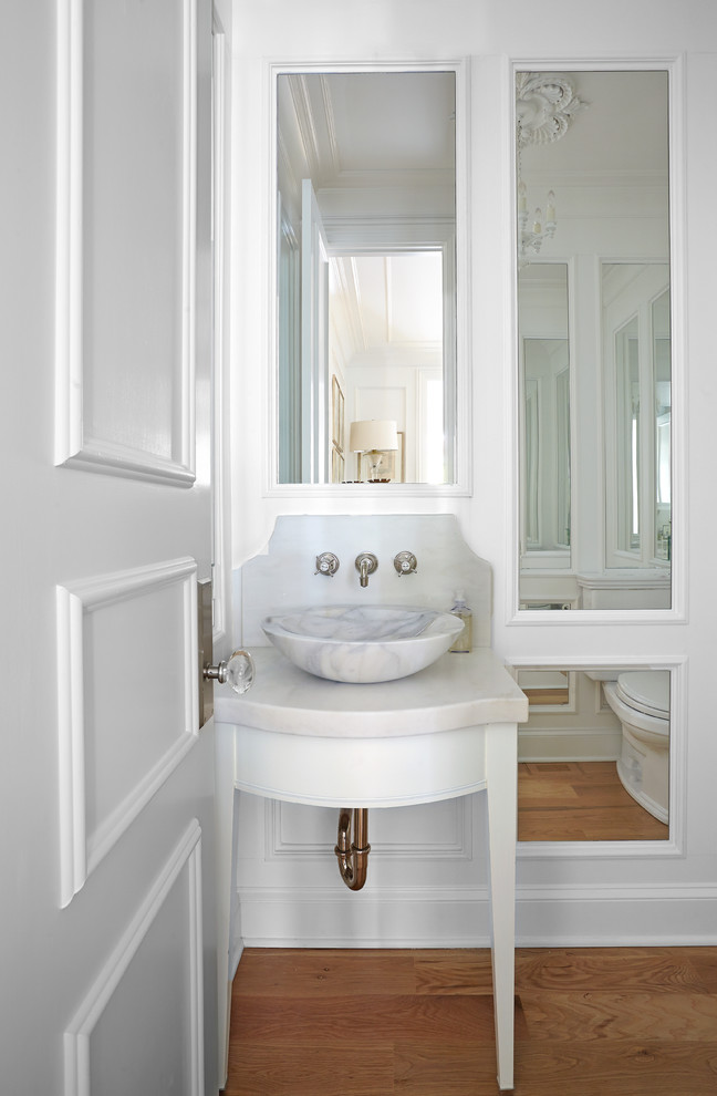 Exemple d'un petit WC suspendu chic avec des portes de placard blanches, un carrelage blanc, des dalles de pierre, un mur blanc, parquet clair, un lavabo de ferme et un plan de toilette en marbre.