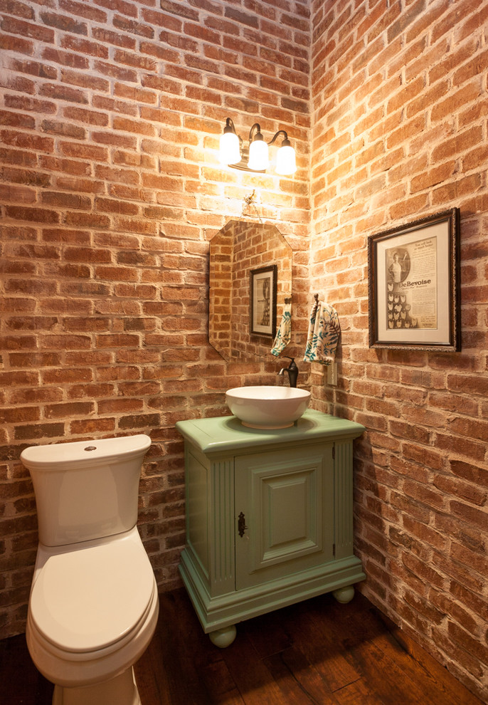 Inredning av ett rustikt litet grön grönt toalett, med ett fristående handfat, möbel-liknande, gröna skåp, träbänkskiva, mellanmörkt trägolv och en toalettstol med separat cisternkåpa