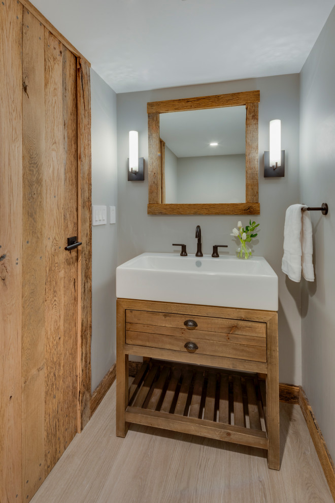 Idée de décoration pour un petit WC et toilettes en bois vieilli avec un placard en trompe-l'oeil, WC à poser, un mur gris, parquet clair, une vasque et un plan de toilette blanc.