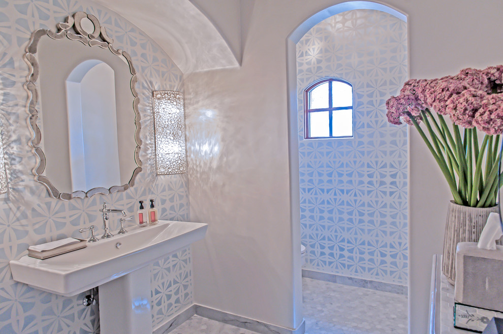 На фото: большой туалет в стиле неоклассика (современная классика) с раковиной с пьедесталом, раздельным унитазом, белой плиткой и мраморным полом с