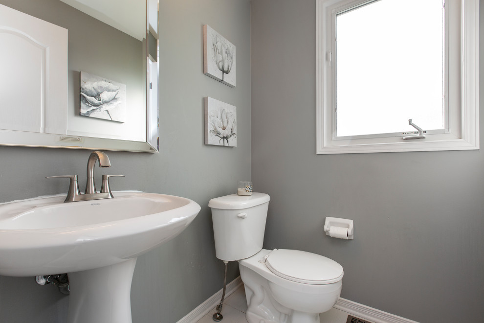 Immagine di un piccolo bagno di servizio chic con WC a due pezzi, pareti grigie, pavimento in gres porcellanato, lavabo a colonna e pavimento bianco