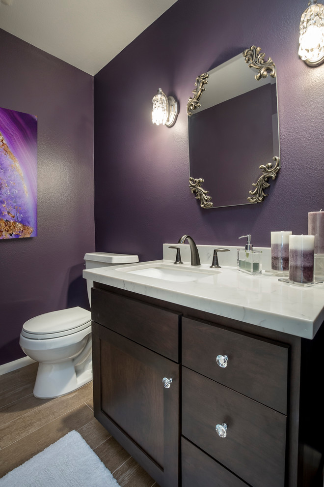 Cette image montre un WC et toilettes traditionnel en bois foncé de taille moyenne avec un placard à porte plane, WC séparés, un mur violet, un sol en carrelage de porcelaine, un lavabo encastré, un plan de toilette en quartz modifié et un sol beige.