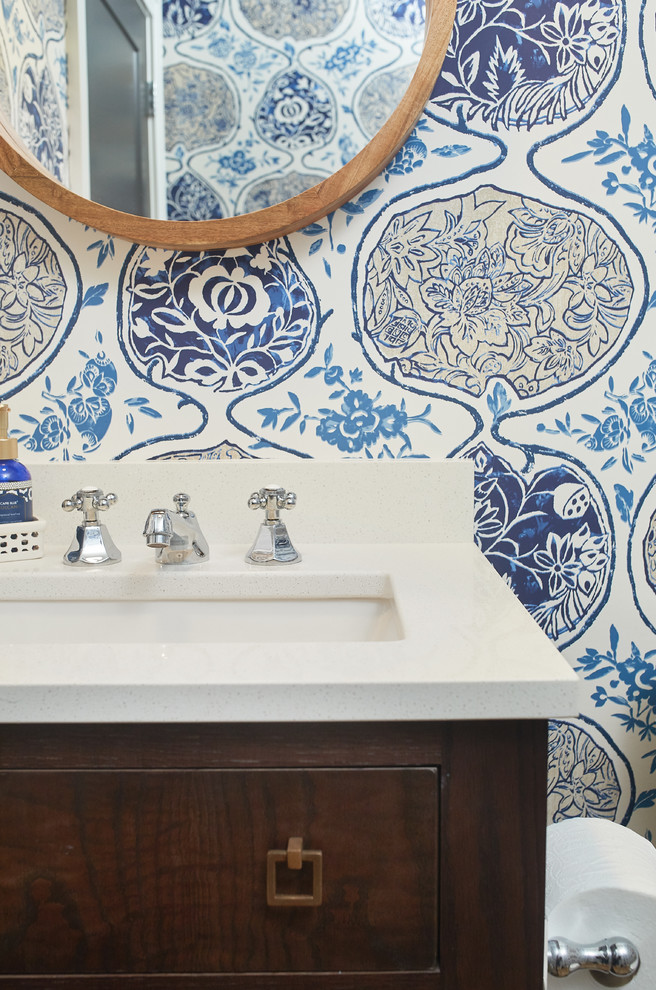 Immagine di un bagno di servizio tradizionale con consolle stile comò, ante marroni, pareti blu, pavimento in legno massello medio, lavabo sottopiano, top in quarzo composito, pavimento marrone e top bianco