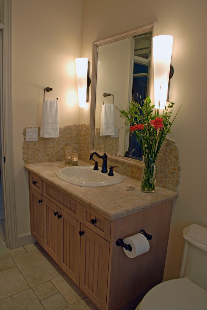 Example of a mid-sized arts and crafts beige tile and pebble tile ceramic tile powder room design in Vancouver with shaker cabinets, light wood cabinets, a one-piece toilet, white walls, a drop-in sink and granite countertops