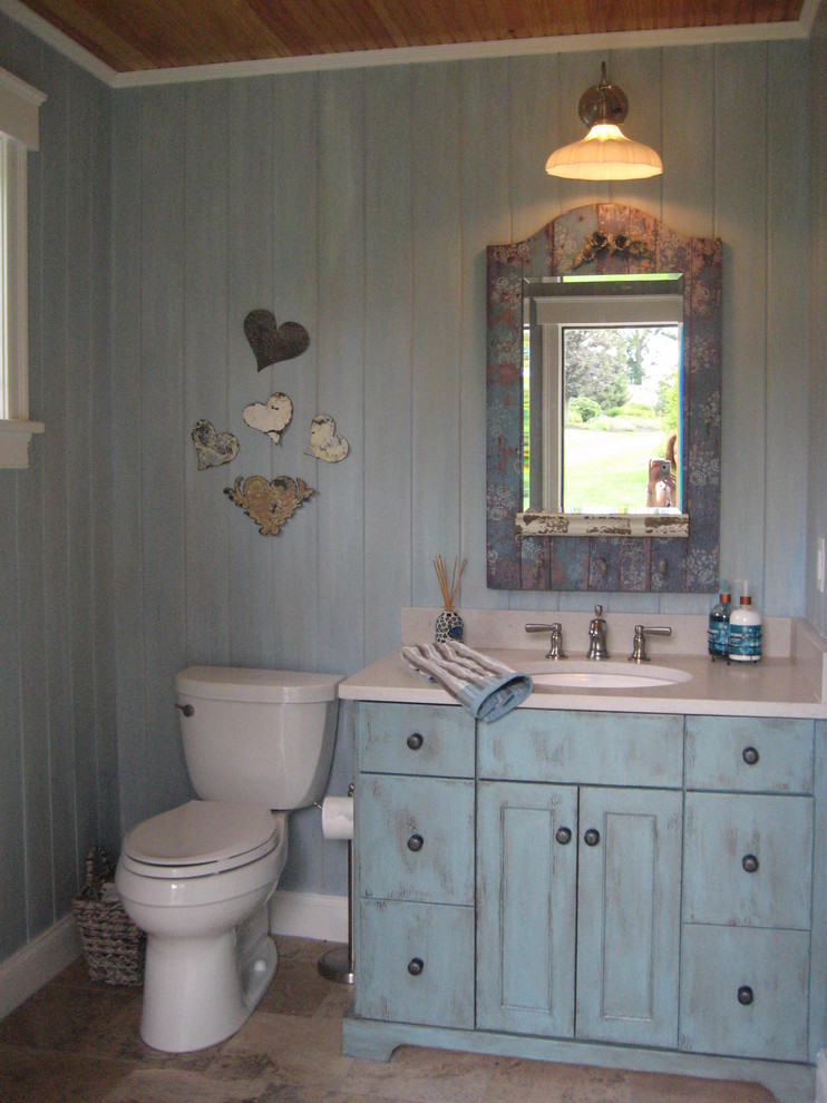 Imagen de aseo ecléctico pequeño con puertas de armario azules, paredes azules, suelo de travertino y encimeras beige