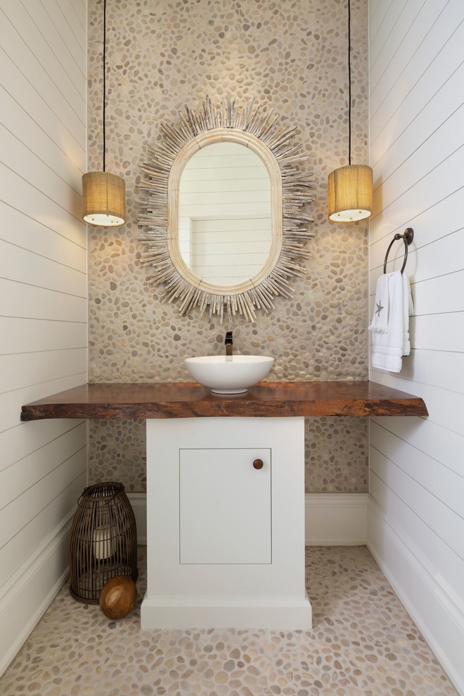 Bild på ett tropiskt brun brunt toalett, med släta luckor, vita skåp, flerfärgad kakel, kakel i småsten, vita väggar, klinkergolv i småsten, ett fristående handfat, träbänkskiva och flerfärgat golv