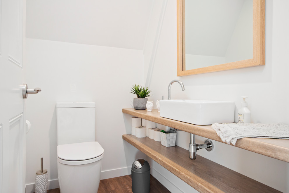 Inspiration for a medium sized contemporary cloakroom in Auckland with open cabinets, a one-piece toilet, white walls, a vessel sink, wooden worktops, brown floors, beige worktops and a floating vanity unit.
