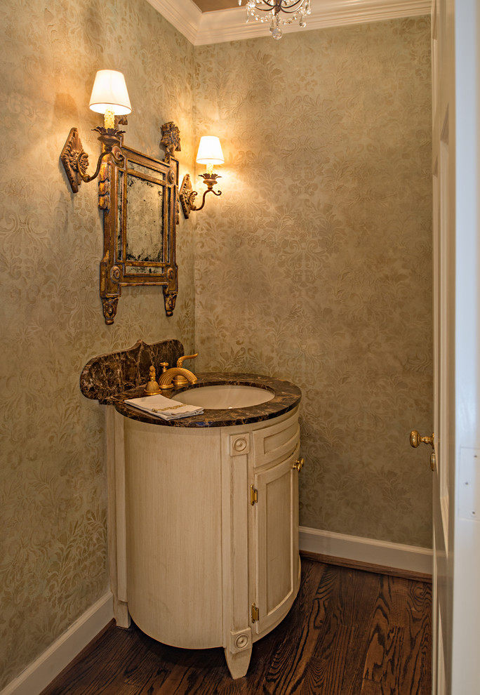 Cette photo montre un petit WC et toilettes chic avec un lavabo encastré, un plan de toilette en granite, WC à poser, un mur beige et un sol en bois brun.