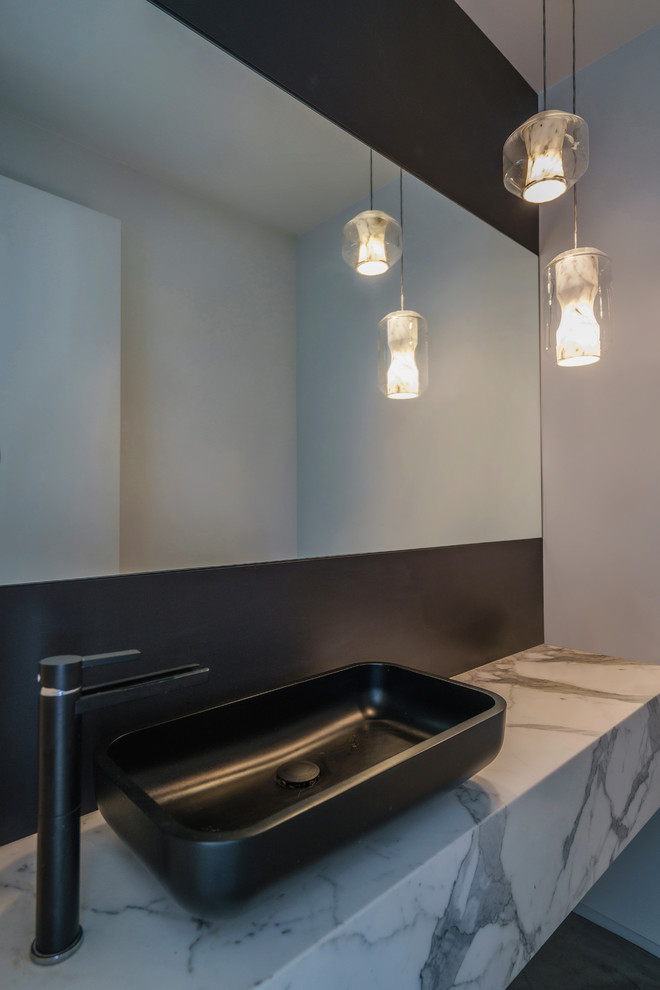 На фото: туалет в стиле модернизм с черной плиткой, плиткой из листового камня, черными стенами, настольной раковиной и мраморной столешницей