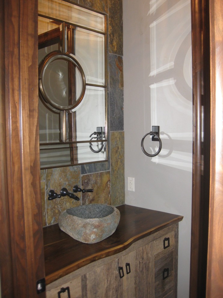 Photo of a small rustic cloakroom in Dallas with shaker cabinets, medium wood cabinets, grey tiles, stone tiles, white walls, a vessel sink and wooden worktops.