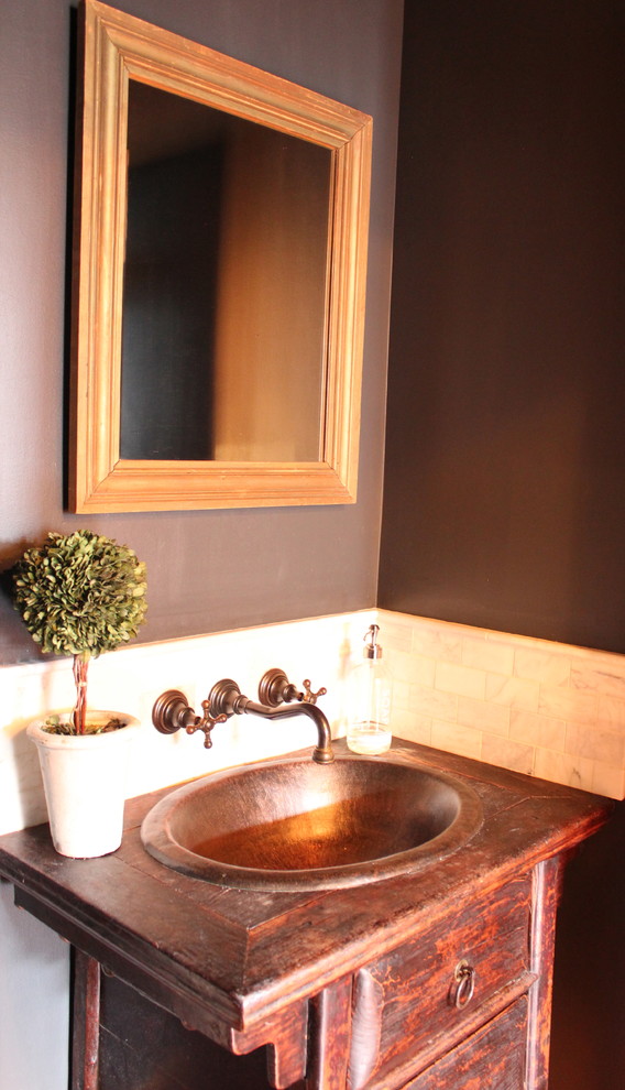 Modelo de aseo de estilo americano con lavabo encastrado, encimera de madera, baldosas y/o azulejos blancos, paredes azules y suelo de madera en tonos medios