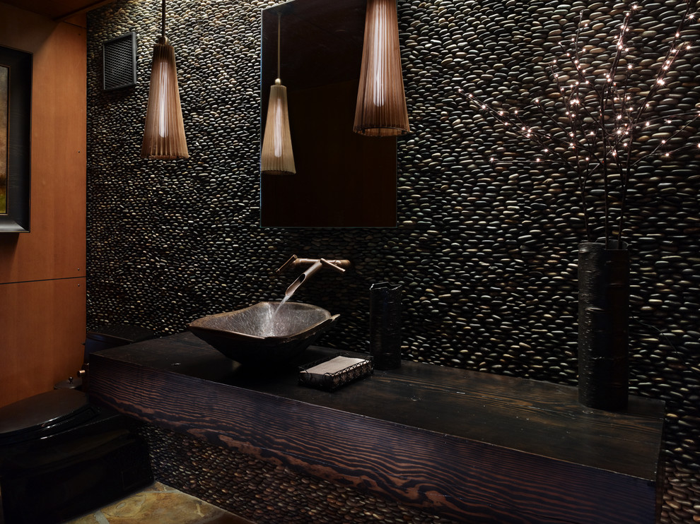 シアトルにあるラスティックスタイルのおしゃれなトイレ・洗面所 (ベッセル式洗面器、木製洗面台、石タイル、ブラウンの洗面カウンター) の写真