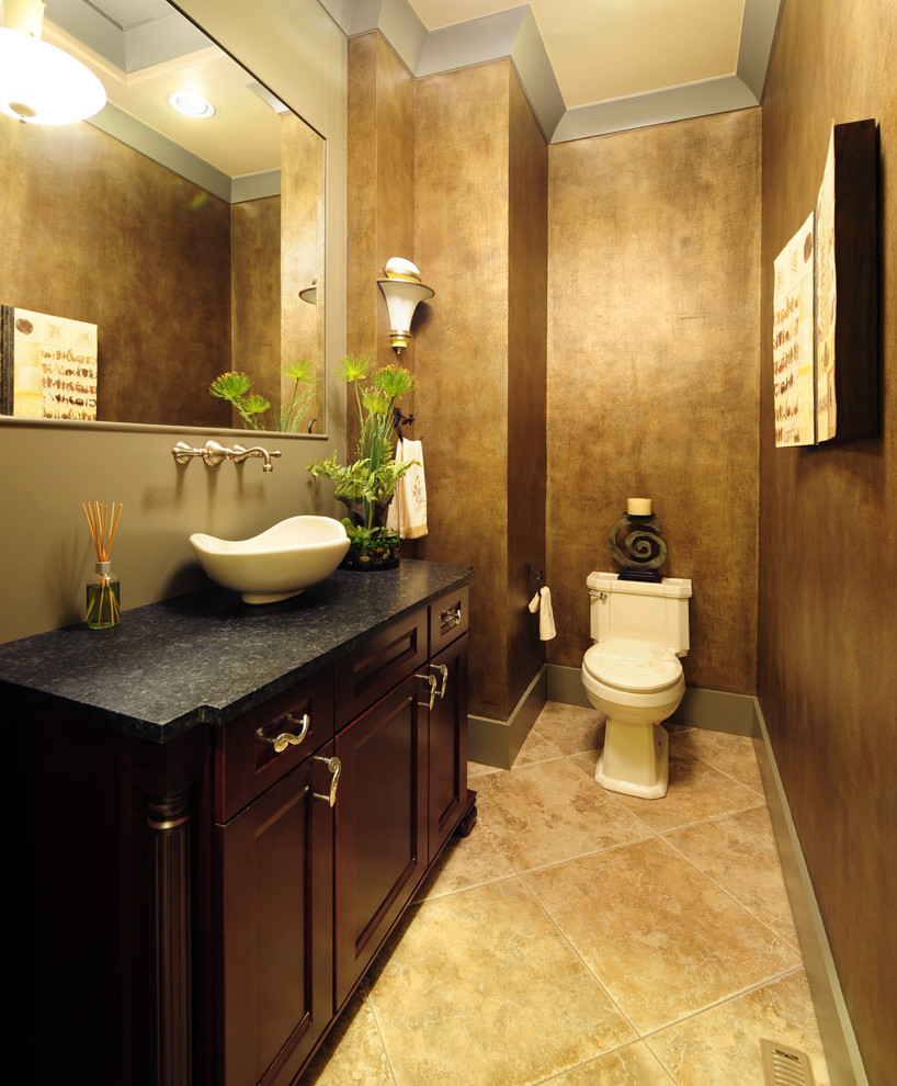 Inredning av ett modernt mellanstort toalett, med ett fristående handfat, luckor med infälld panel, skåp i mörkt trä, granitbänkskiva, en toalettstol med hel cisternkåpa, beige kakel, klinkergolv i keramik, beige väggar och beiget golv