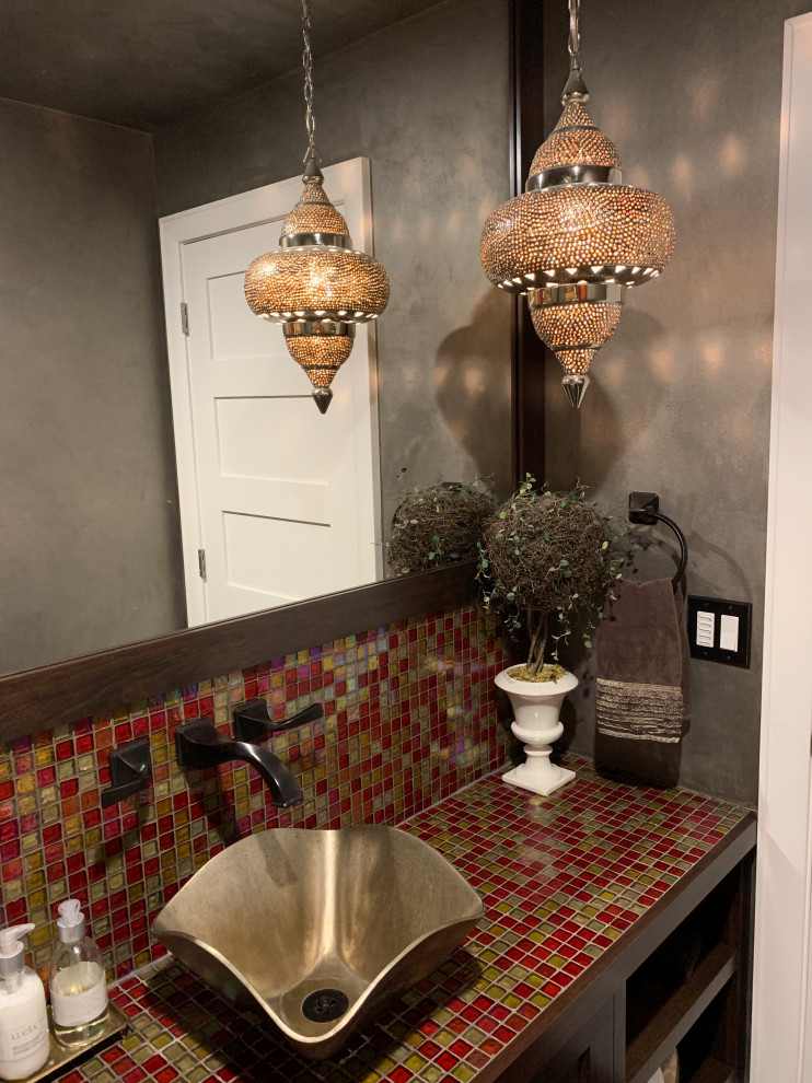 На фото: туалет среднего размера в средиземноморском стиле с разноцветной плиткой, стеклянной плиткой, серыми стенами, настольной раковиной, столешницей из плитки и разноцветной столешницей с