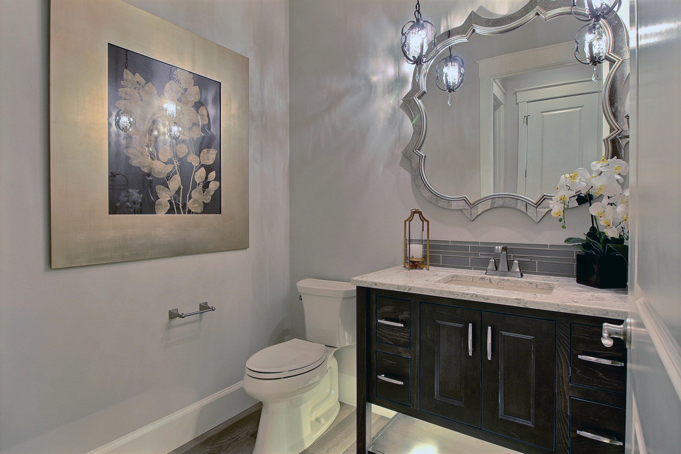 Powder room - mid-sized transitional gray tile and porcelain tile light wood floor and brown floor powder room idea in Portland with recessed-panel cabinets, dark wood cabinets, a two-piece toilet, gray walls, an undermount sink and quartz countertops