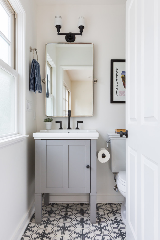 Пример оригинального дизайна: туалет среднего размера в современном стиле с бетонным полом, фасадами в стиле шейкер, серыми фасадами, раздельным унитазом, белыми стенами, монолитной раковиной и разноцветным полом