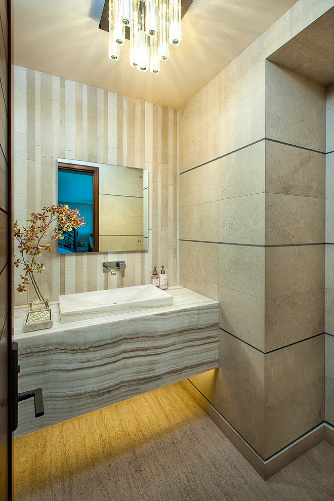 На фото: туалет среднего размера в современном стиле с монолитной раковиной, столешницей из оникса, бежевой плиткой, бежевыми стенами, полом из известняка и плиткой из известняка