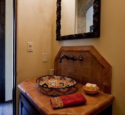 Imagen de aseo mediterráneo con lavabo sobreencimera, baldosas y/o azulejos naranja y paredes beige