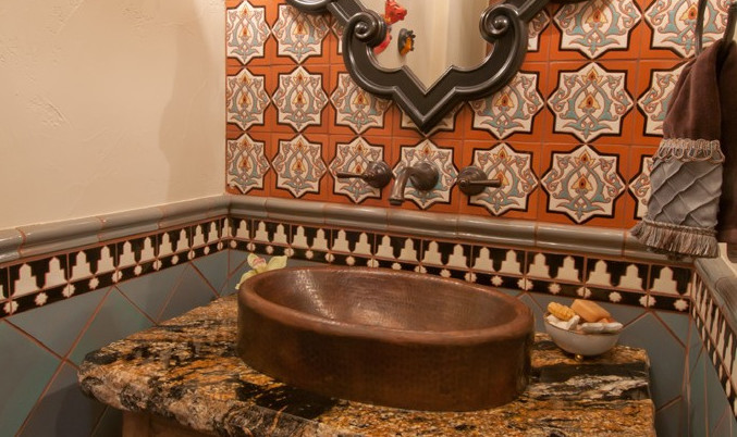 Immagine di un bagno di servizio mediterraneo con lavabo a bacinella, piastrelle arancioni, piastrelle multicolore, piastrelle in ceramica, WC a due pezzi e pareti arancioni