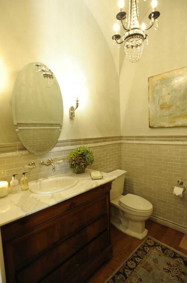Inspiration for a medium sized traditional cloakroom in Other with a two-piece toilet, beige tiles, medium hardwood flooring, shaker cabinets, medium wood cabinets, porcelain tiles, white walls, a built-in sink and marble worktops.