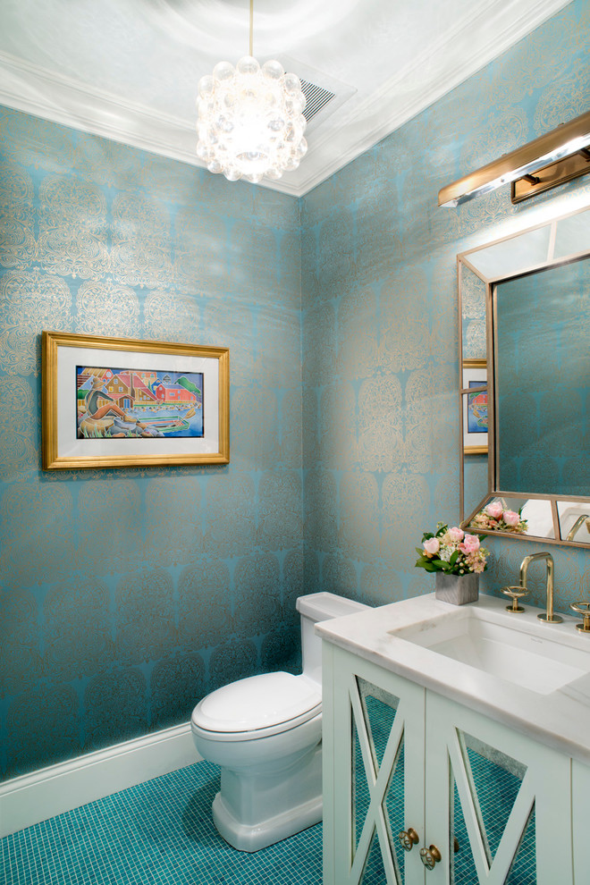 Klassisk inredning av ett toalett, med luckor med glaspanel, vita skåp, en toalettstol med separat cisternkåpa, blå kakel, blå väggar, mosaikgolv, marmorbänkskiva och ett undermonterad handfat