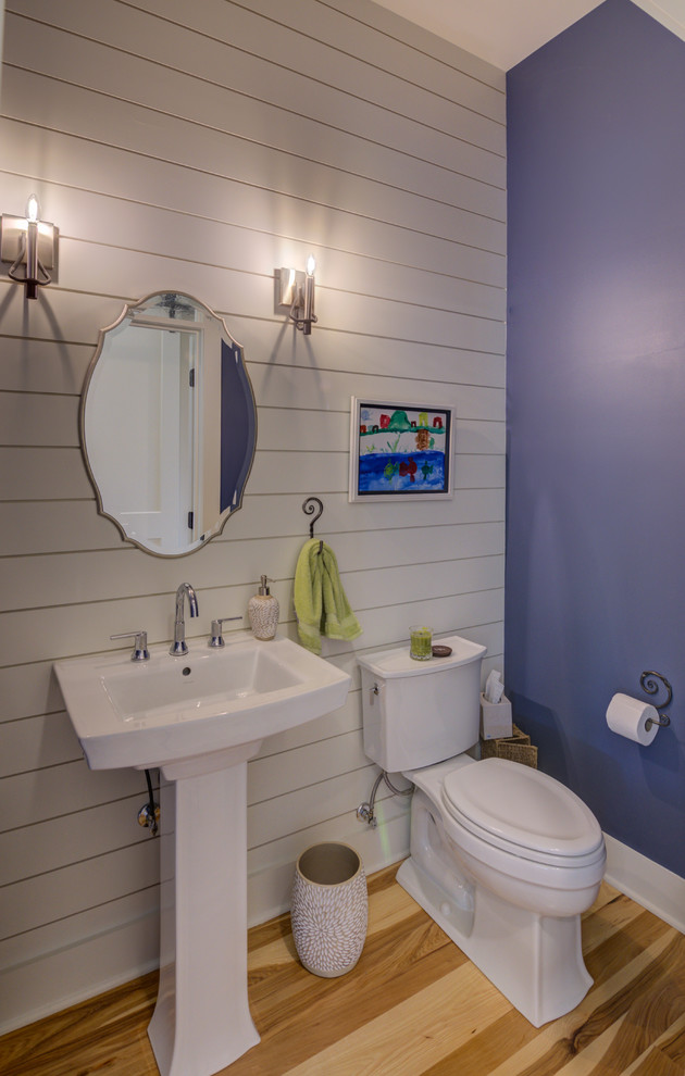 Moderne Gästetoilette mit Toilette mit Aufsatzspülkasten, blauer Wandfarbe, hellem Holzboden und Sockelwaschbecken in Indianapolis
