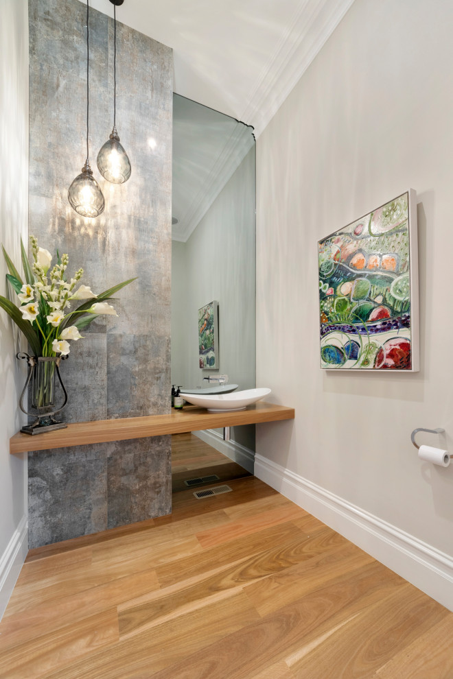 Moderne Gästetoilette mit grauen Fliesen, beiger Wandfarbe, braunem Holzboden, Aufsatzwaschbecken, Waschtisch aus Holz, braunem Boden und brauner Waschtischplatte in Melbourne