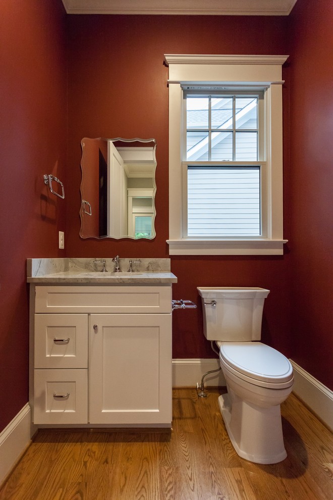 Foto di un bagno di servizio country con ante in stile shaker, ante bianche, WC a due pezzi, pareti rosse, parquet chiaro, lavabo sottopiano, pavimento beige e top grigio