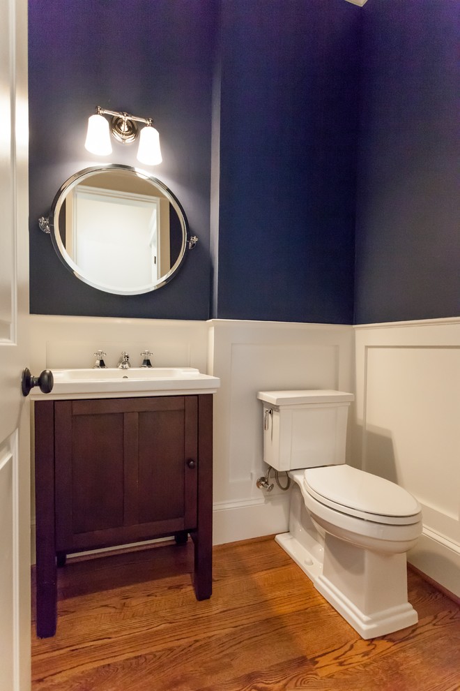 Idee per un bagno di servizio country con consolle stile comò, ante in legno bruno, WC a due pezzi, pareti blu, pavimento in legno massello medio, pavimento marrone e top bianco