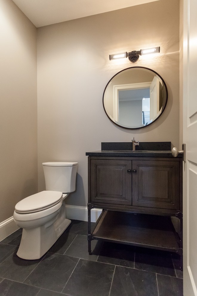 Aménagement d'un WC et toilettes classique en bois foncé avec un placard en trompe-l'oeil, WC séparés, un mur beige, un lavabo encastré, un sol gris et un plan de toilette noir.