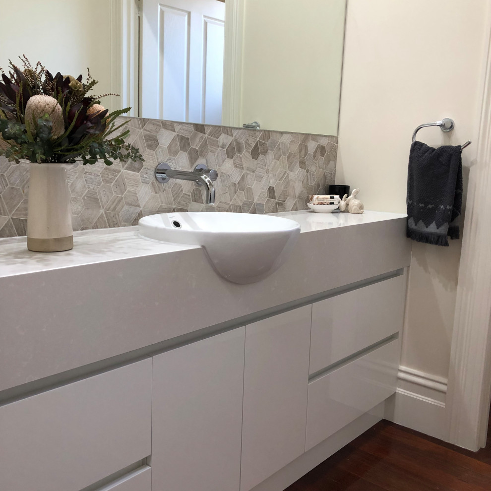 Exempel på ett mellanstort modernt beige beige toalett, med möbel-liknande, vita skåp, flerfärgad kakel, keramikplattor, flerfärgade väggar, mellanmörkt trägolv, ett integrerad handfat, bänkskiva i kvartsit och brunt golv