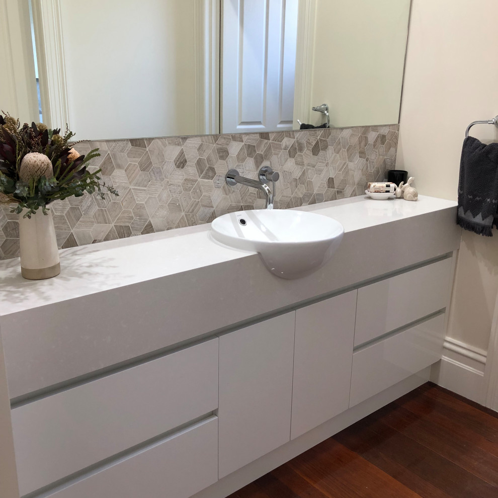 Idéer för ett mellanstort modernt beige toalett, med möbel-liknande, vita skåp, flerfärgad kakel, keramikplattor, flerfärgade väggar, mellanmörkt trägolv, ett integrerad handfat, bänkskiva i kvartsit och brunt golv