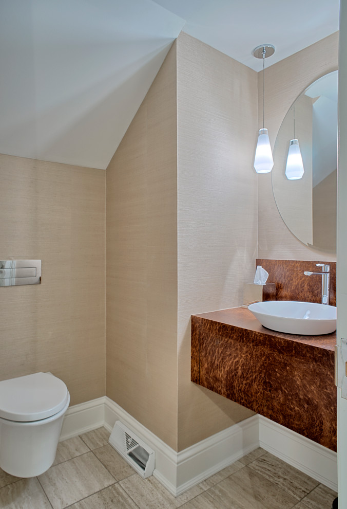 This is an example of a medium sized modern cloakroom in Chicago with a wall mounted toilet, beige walls, porcelain flooring, a vessel sink, beige floors, flat-panel cabinets, medium wood cabinets, wooden worktops, brown worktops, a floating vanity unit and wallpapered walls.