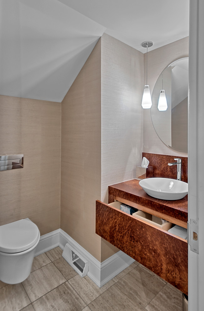 Inspiration for a medium sized modern cloakroom in Chicago with a wall mounted toilet, beige walls, porcelain flooring, a vessel sink, beige floors, flat-panel cabinets, medium wood cabinets, wooden worktops, brown worktops, a floating vanity unit and wallpapered walls.