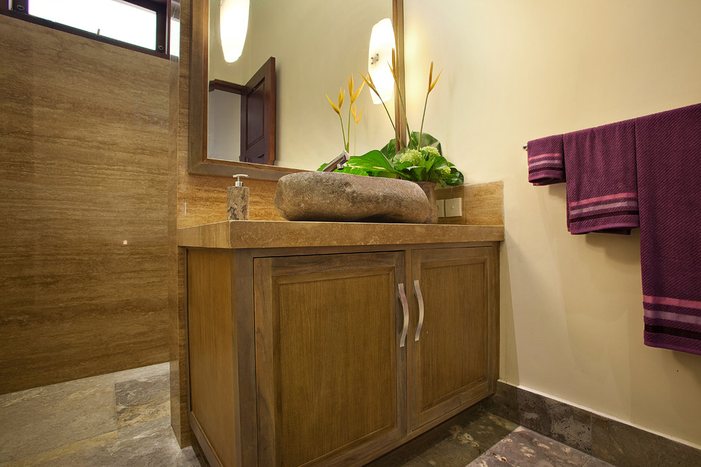 Example of a mid-sized beige tile and stone tile powder room design in Other with a vessel sink, recessed-panel cabinets, beige walls and medium tone wood cabinets