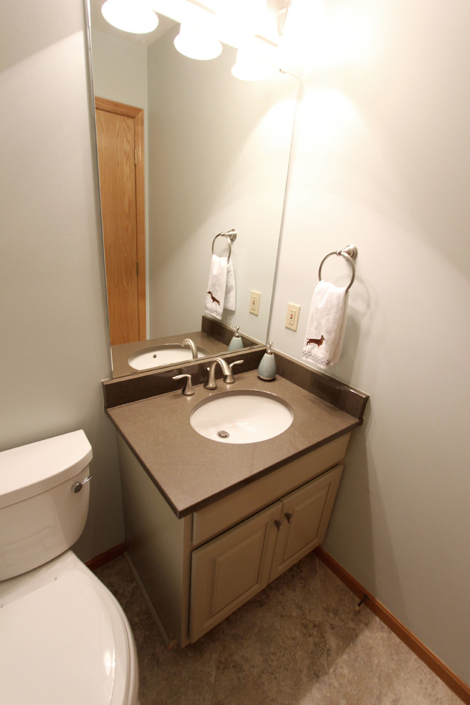 Powder room - small traditional powder room idea in Cleveland with raised-panel cabinets, beige cabinets, a two-piece toilet, green walls, an undermount sink, quartz countertops and brown countertops