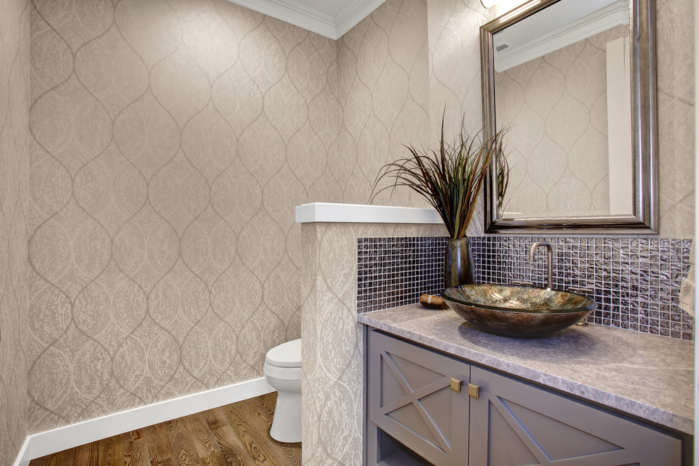 Idéer för att renovera ett amerikanskt toalett, med möbel-liknande, grå skåp, en toalettstol med separat cisternkåpa, grå kakel, glaskakel, flerfärgade väggar, mellanmörkt trägolv, ett fristående handfat och marmorbänkskiva